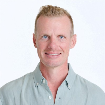 Professional man with light hair in light blue shirt smiling in corporate setting